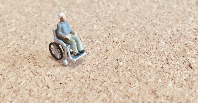 広い場所にひとりで座る、車椅子の人のミニチュア