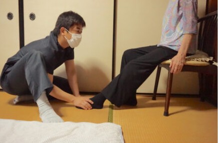 ご自宅の和室で、足元を確認しながら運動を行う理学療法士